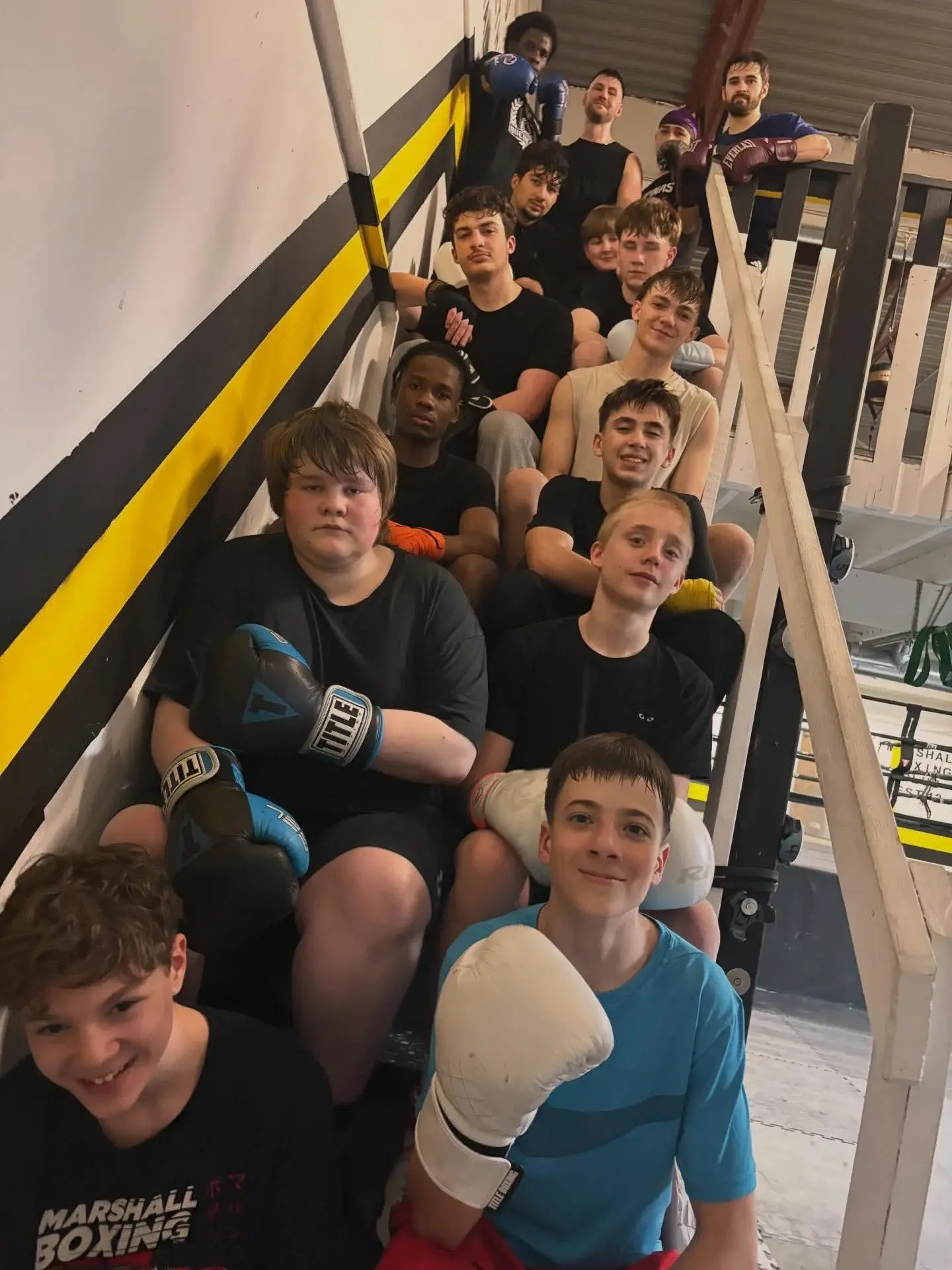 Club members with boxing gloves gathered on the gym staircase