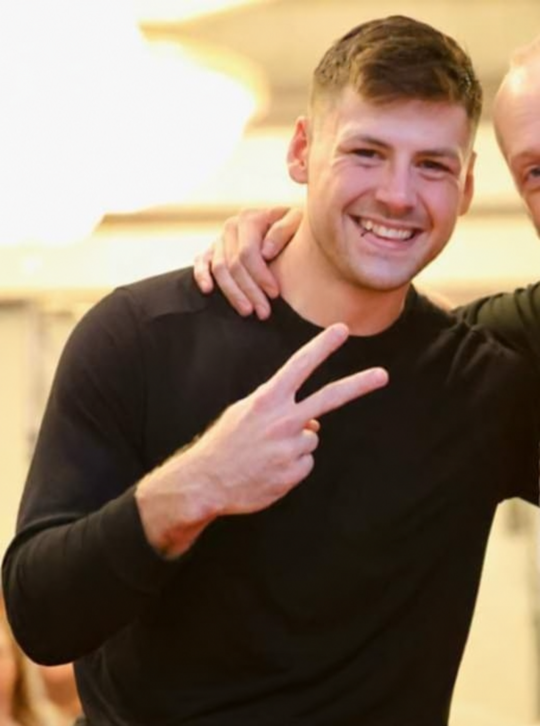 Noah Atlas smiling and holding up a peace sign