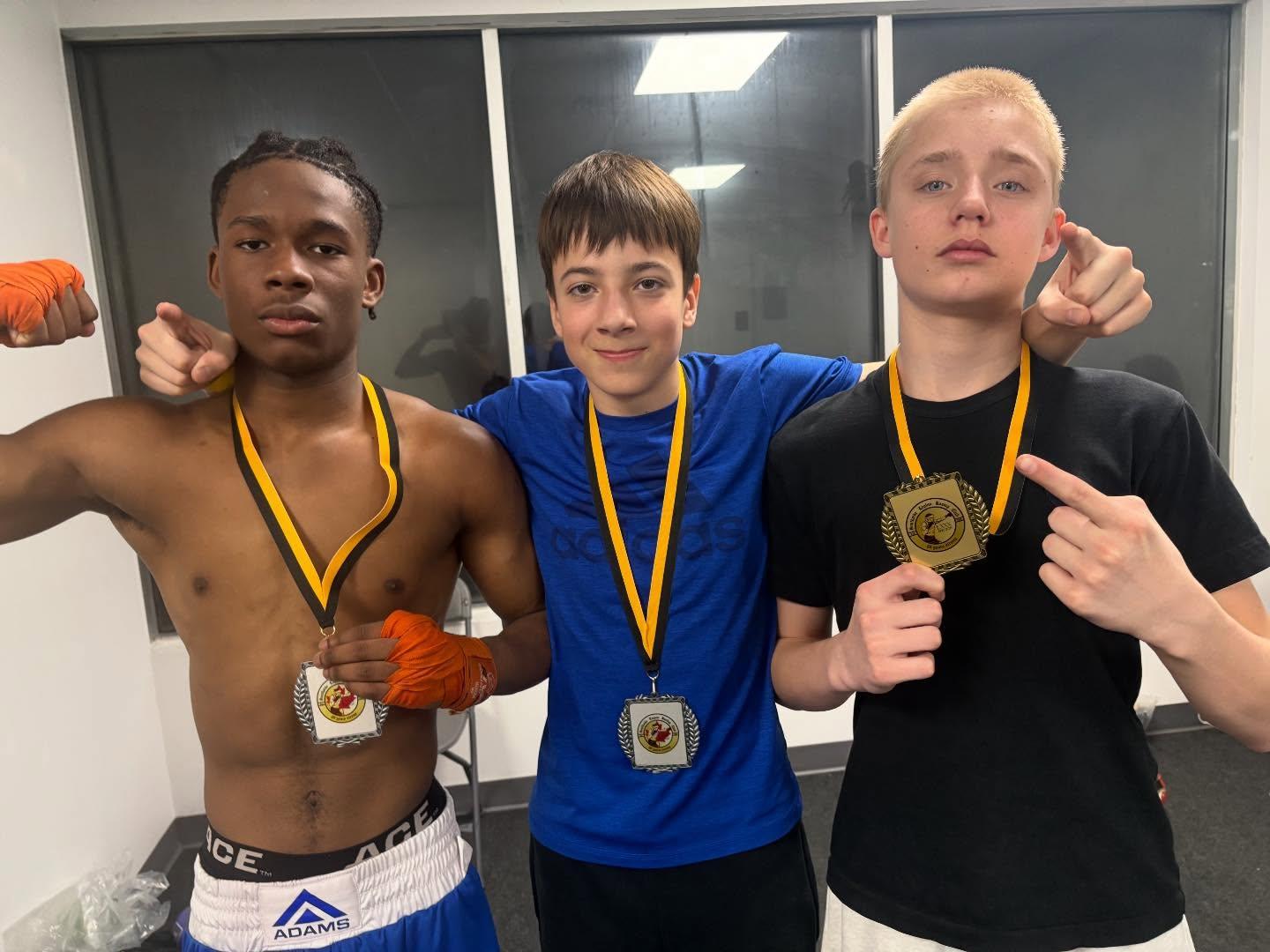 Three young boxers displaying their medals